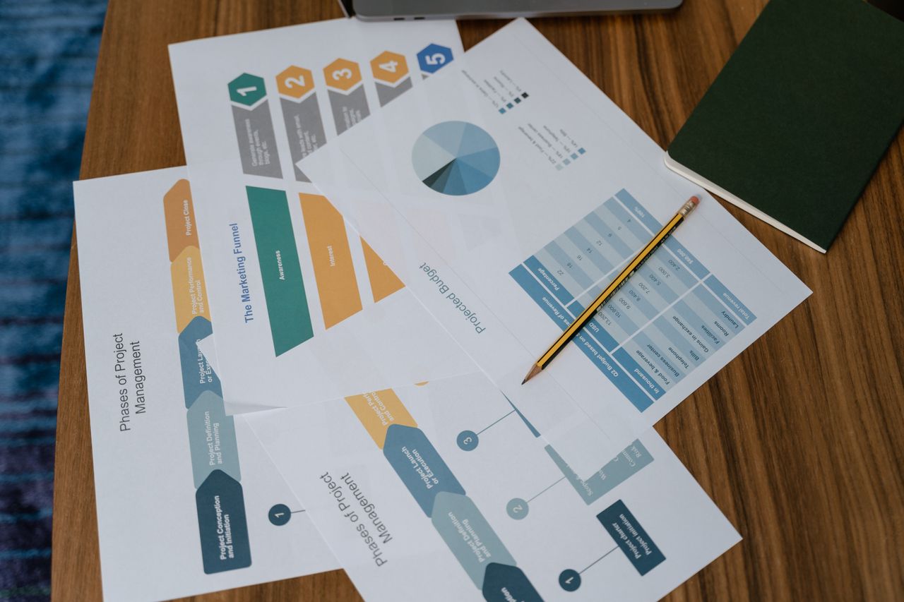 Vue de dessus de documents de gestion de projet et de graphiques sur un bureau avec un crayon.